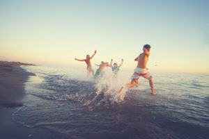 Group of friends running in to sea at sunset