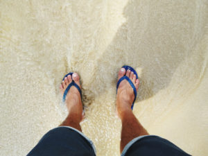 Low Section Of Man Standing On Beach