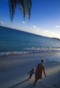 Mother and daughter walk along white sand beach
