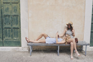 Tourist girls relax in European village using smart phone to connect on adventure travel