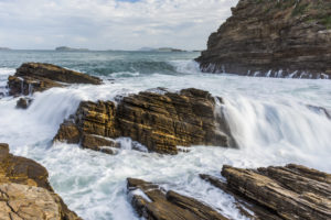 Strong waves crashing over rocks in Praia da Ferradurinha, Armação de Búzios, Rio de Janeiro, Brazil
